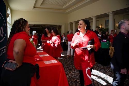 A lady in red talking to another lady in red at a tshirt table